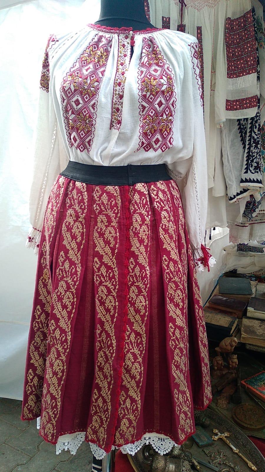 Costum popular românesc autentic: ie albă brodată cu motive roșii și aurii și catrință roșie cu alesături tradiționale